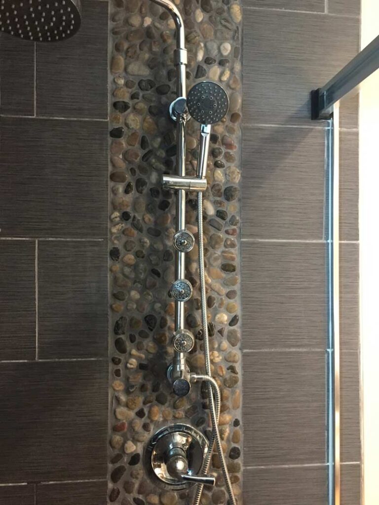 Multi head shower panel mounted on rock accent stripe tile